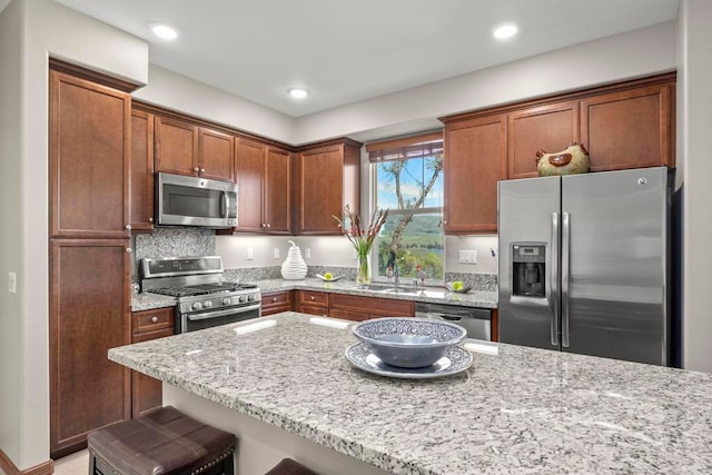 kitchen with a breakfast bar, sink, decorative backsplash, light stone countertops, and stainless steel appliances