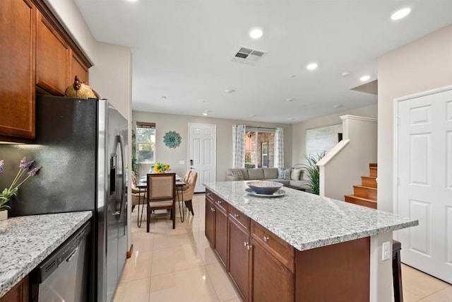 kitchen featuring light stone countertops, a center island, light tile patterned floors, and appliances with stainless steel finishes