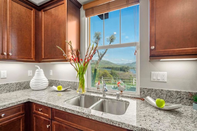 kitchen featuring a mountain view, light stone counters, plenty of natural light, and sink