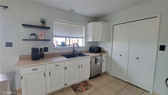 kitchen with sink, white cabinets, stainless steel dishwasher, and light tile patterned flooring