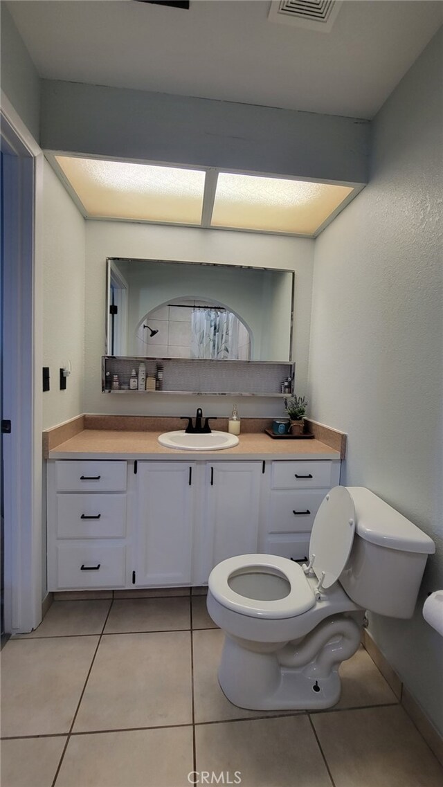 bathroom with toilet, tile patterned floors, and vanity