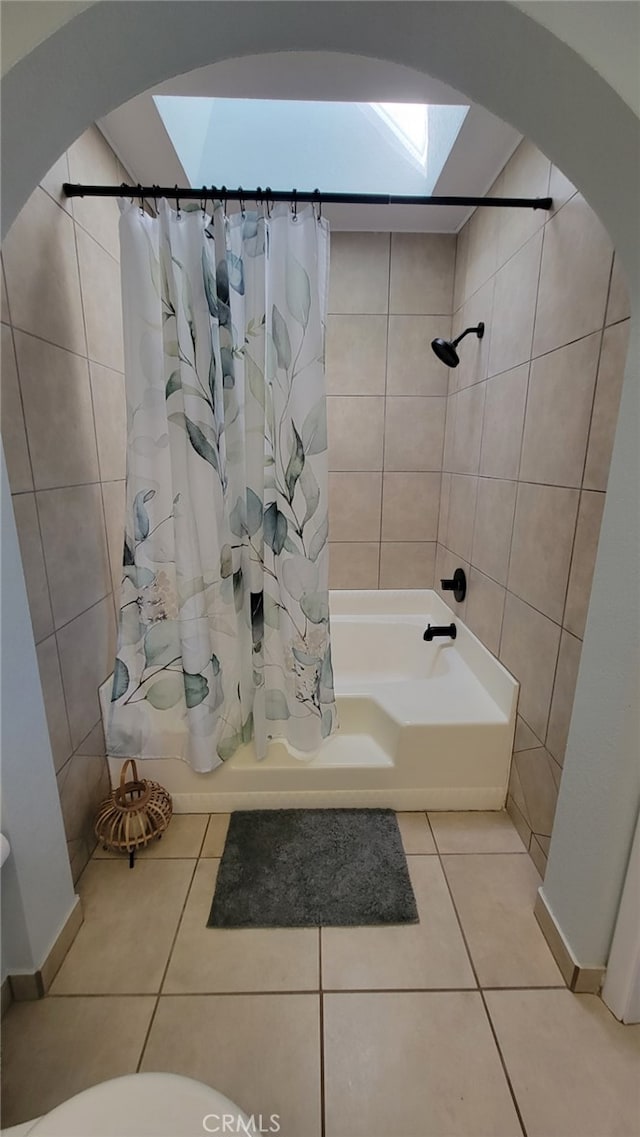 bathroom with tile walls, tile patterned floors, a skylight, and shower / tub combo