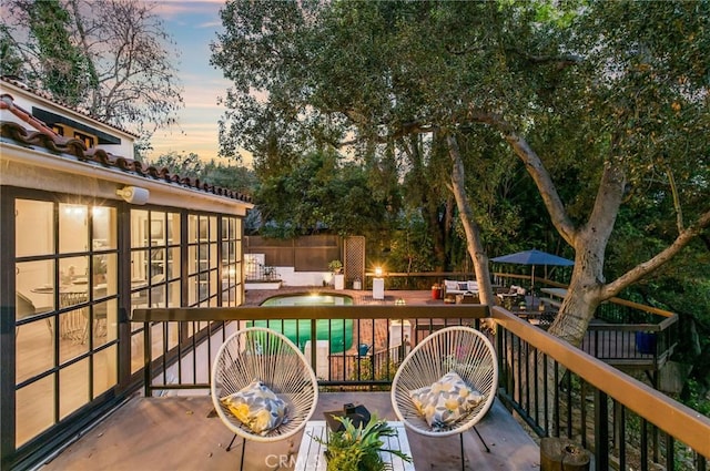 deck at dusk featuring a swimming pool