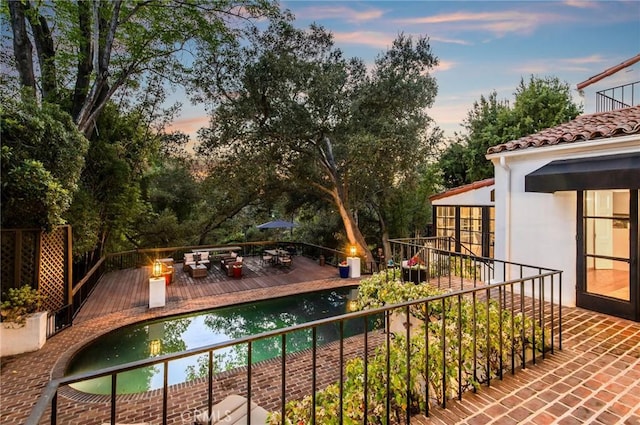 pool at dusk featuring a deck