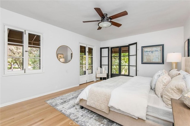 bedroom featuring hardwood / wood-style floors, ceiling fan, multiple windows, and french doors