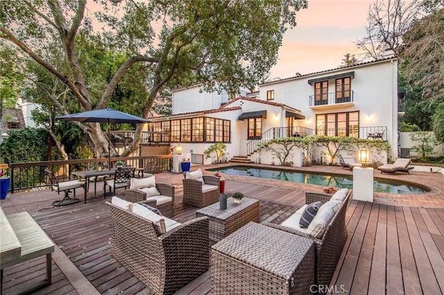 deck at dusk with a swimming pool with hot tub