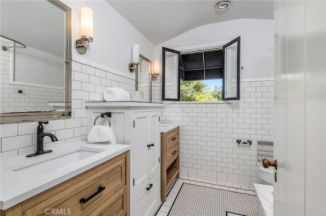 bathroom featuring tile patterned flooring, vanity, vaulted ceiling, and tile walls