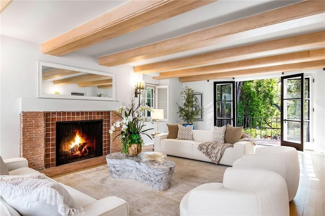 living room with beam ceiling, light wood-type flooring, and a tile fireplace