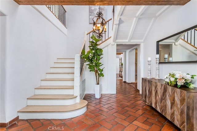 stairs with lofted ceiling with beams and a notable chandelier