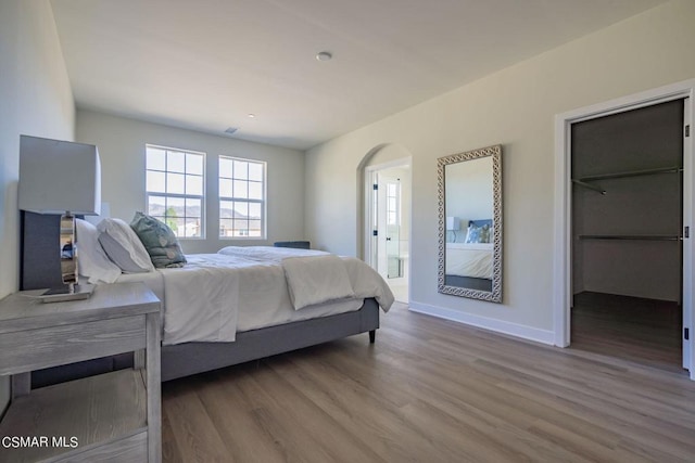 bedroom with hardwood / wood-style flooring and a spacious closet