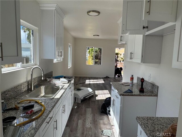 kitchen featuring stone countertops, dark hardwood / wood-style flooring, sink, and white cabinets