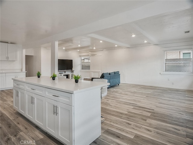 143 N Hobart Blvd, Los Angeles, CA 90004 - kitchen featuring beamed ceiling, a kitchen island, white cabinets, and light wood-type flooring