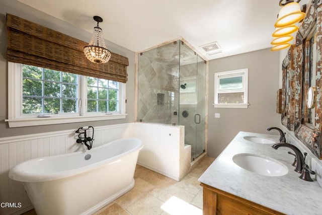full bathroom with a wainscoted wall, a sink, and plenty of natural light
