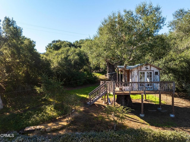 view of play area featuring a forest view, a deck, and stairs