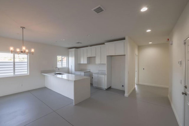 kitchen with a notable chandelier, sink, white cabinetry, and hanging light fixtures