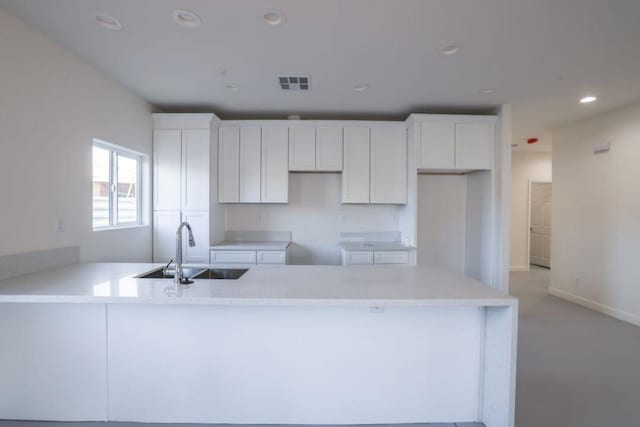 kitchen featuring kitchen peninsula, white cabinetry, and sink