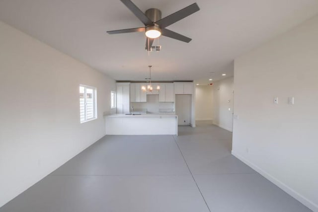 unfurnished living room with sink and ceiling fan with notable chandelier