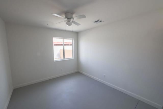 empty room with ceiling fan and concrete flooring