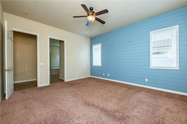 unfurnished bedroom with ceiling fan, wooden walls, and carpet floors