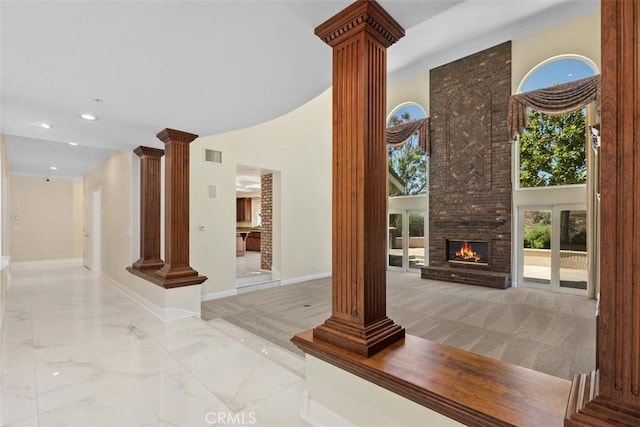 unfurnished living room with a large fireplace, ornate columns, and a towering ceiling