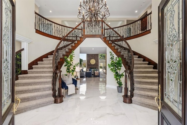 entryway with a towering ceiling, crown molding, and a chandelier