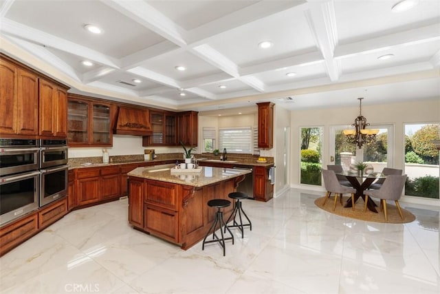 kitchen with beam ceiling, an inviting chandelier, light stone counters, a kitchen island, and custom exhaust hood