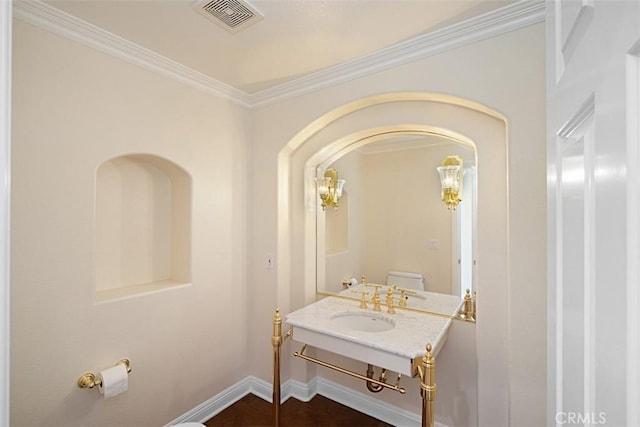 bathroom featuring sink, ornamental molding, and toilet