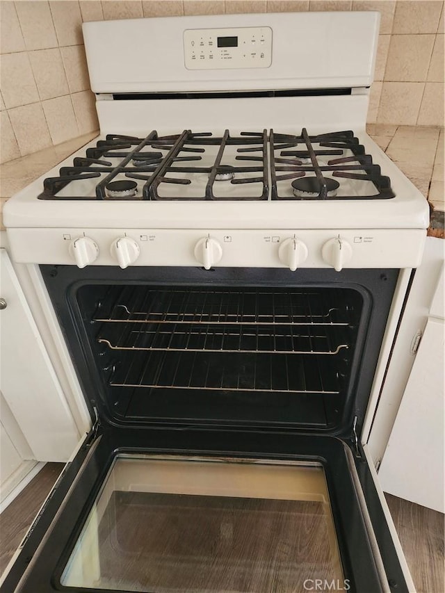 room details with white cabinets, decorative backsplash, and white gas range oven