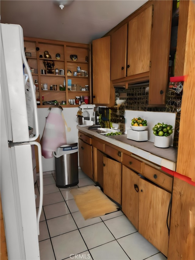 kitchen with light tile patterned flooring, sink, white fridge, and backsplash