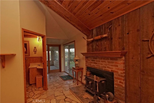 living room featuring wooden walls, wooden ceiling, vaulted ceiling, and a wood stove