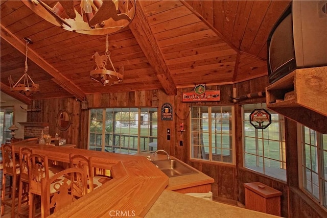 dining space with sink, wooden walls, and wood ceiling