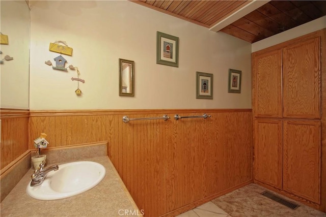 bathroom featuring sink, wood ceiling, wooden walls, and tile patterned floors