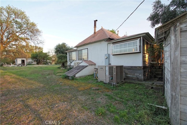 rear view of property featuring central AC and a lawn