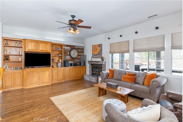 living room with a high end fireplace, light hardwood / wood-style floors, and ceiling fan