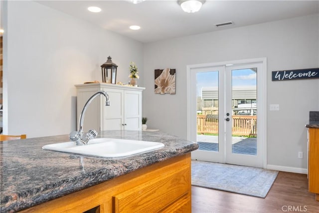 bathroom with hardwood / wood-style flooring, a healthy amount of sunlight, sink, and french doors