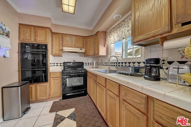 kitchen with tile counters, sink, backsplash, light tile patterned floors, and black appliances