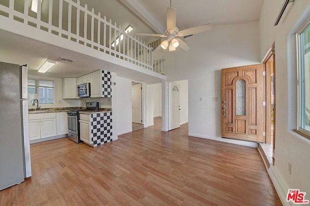 interior space featuring ceiling fan, a towering ceiling, sink, and light hardwood / wood-style flooring