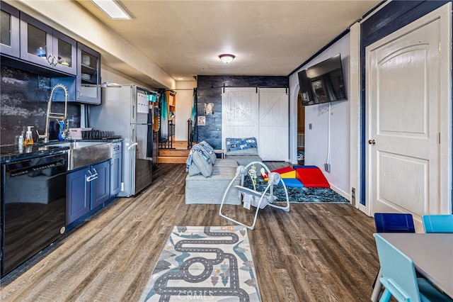 kitchen featuring stainless steel refrigerator, dishwasher, sink, a barn door, and dark hardwood / wood-style floors