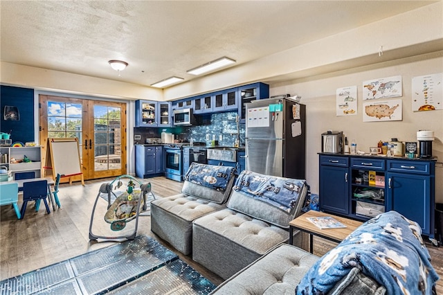 living room featuring indoor bar, french doors, a textured ceiling, and light hardwood / wood-style flooring