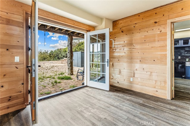 doorway with wood walls and hardwood / wood-style flooring