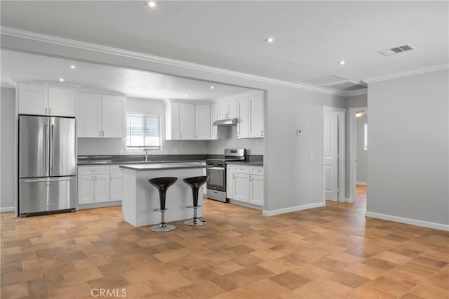 kitchen with white cabinets, a kitchen island, stainless steel appliances, a kitchen breakfast bar, and crown molding