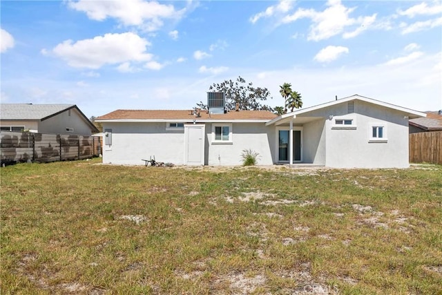 rear view of property with cooling unit and a lawn