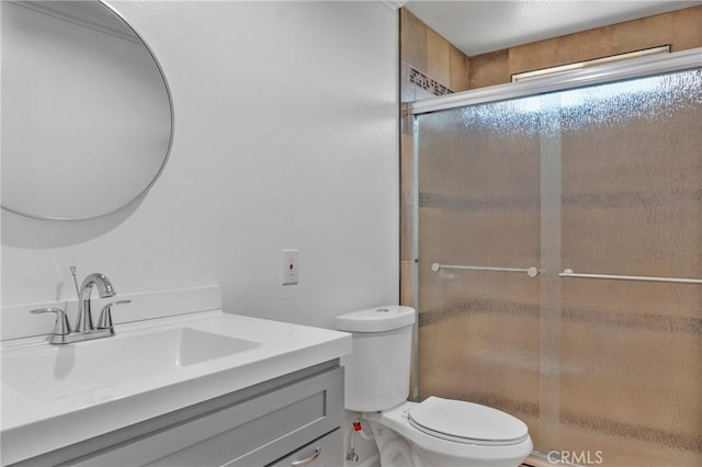 bathroom featuring toilet, vanity, and a shower with door