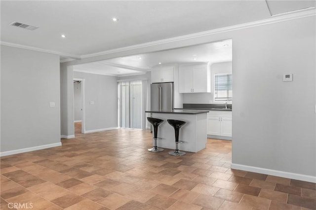 kitchen featuring white cabinetry, high quality fridge, a kitchen island, crown molding, and a breakfast bar