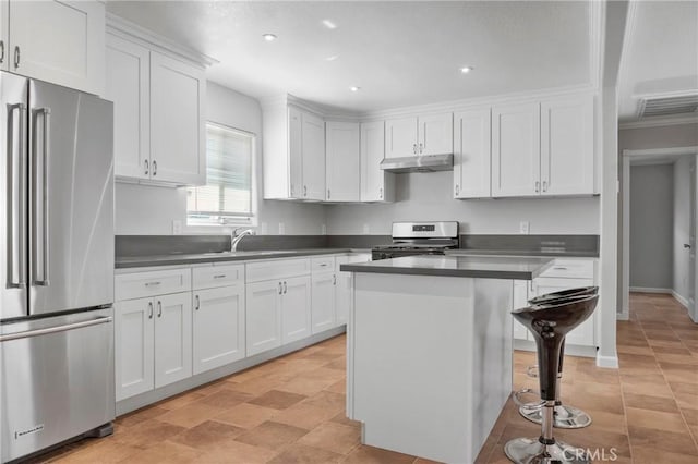 kitchen with white cabinets, appliances with stainless steel finishes, a center island, a kitchen bar, and sink