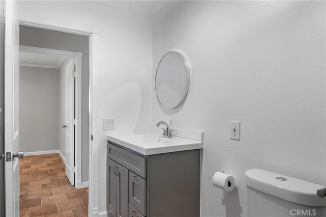 bathroom featuring toilet, crown molding, and vanity