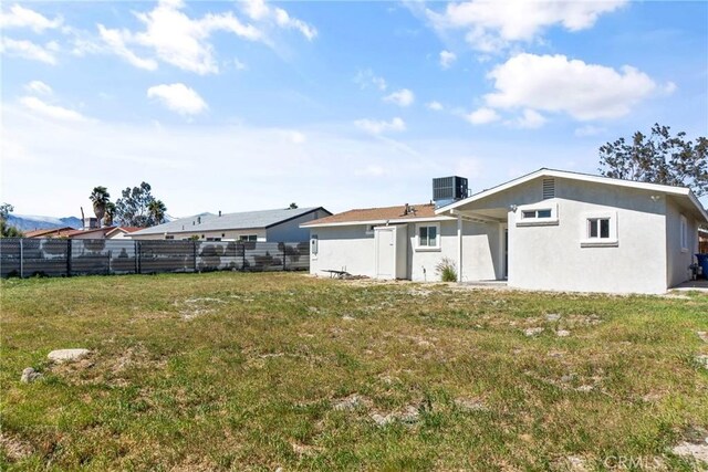 rear view of property with a yard and central AC