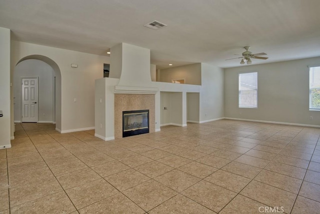 unfurnished living room featuring light tile patterned floors, ceiling fan, and a tiled fireplace