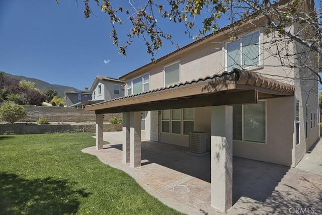 rear view of property featuring a mountain view, a patio area, and a lawn