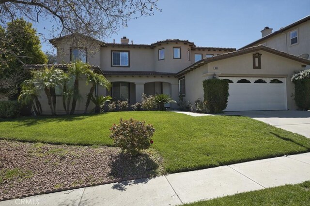 mediterranean / spanish-style home featuring a garage and a front lawn